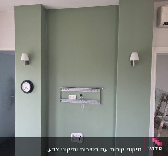 קיר צבוע בירוק עם שעון ומתקן לטלוויזיה